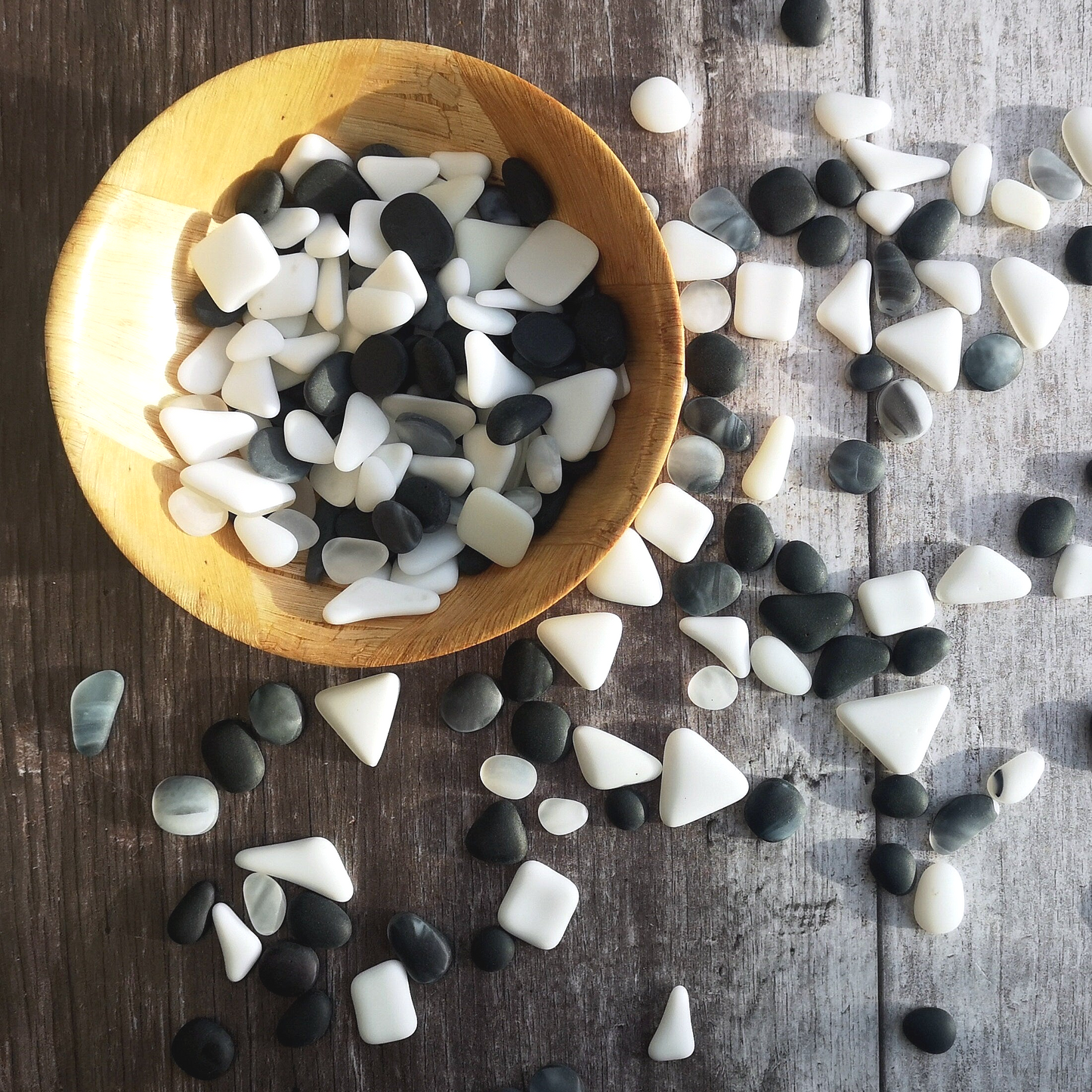 Sustainable black and white tumbled glass collection, displayed on natural wood, highlighting their eco-friendly appeal and artistic value.