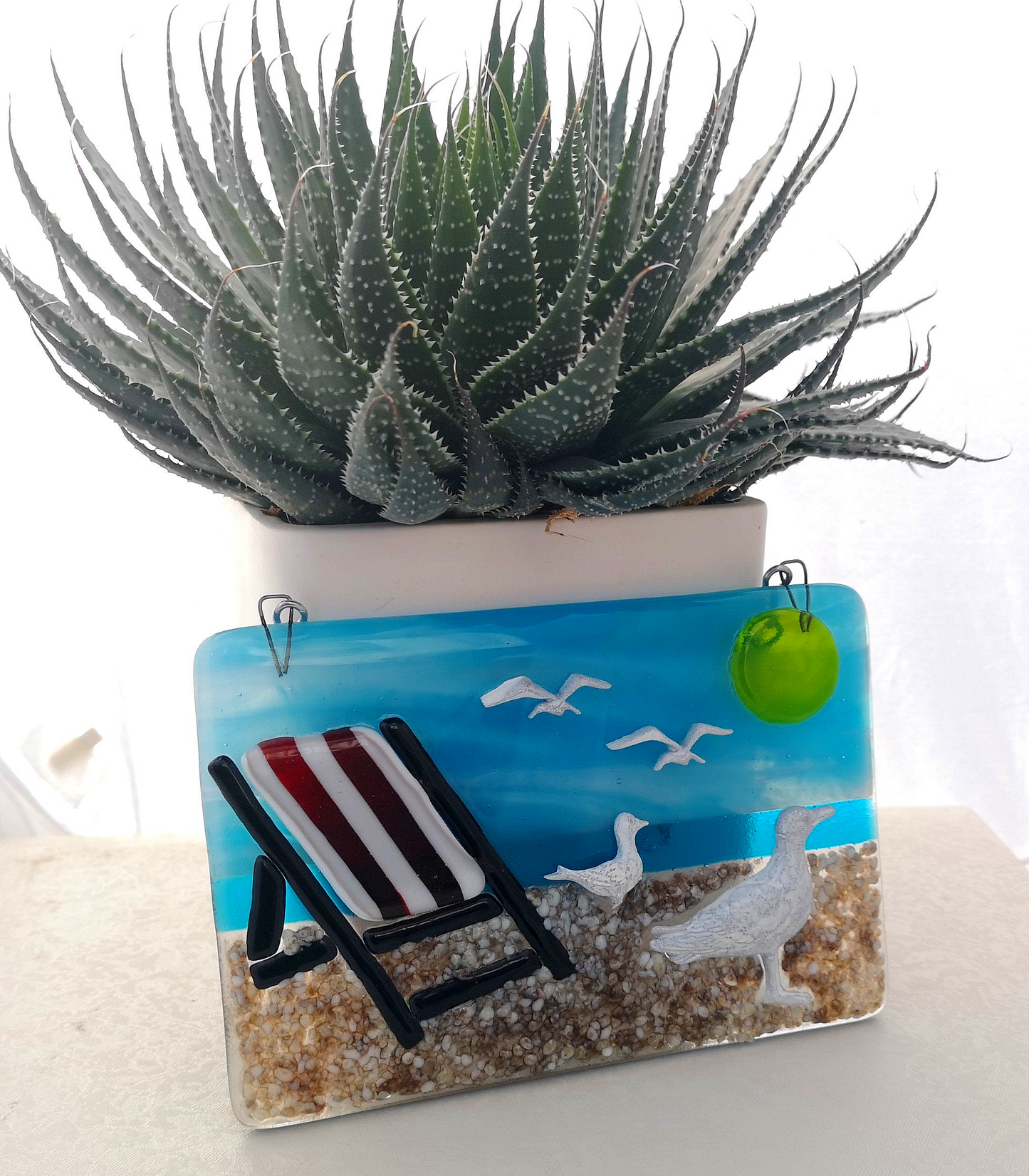 Handmade fused glass 3D Seagull & Deckchair Hanging Picture. Seaside suncatcher wall art, beach gift decoration, sea ocean scene with glass pebbles, sea birds, sun and blue sky.