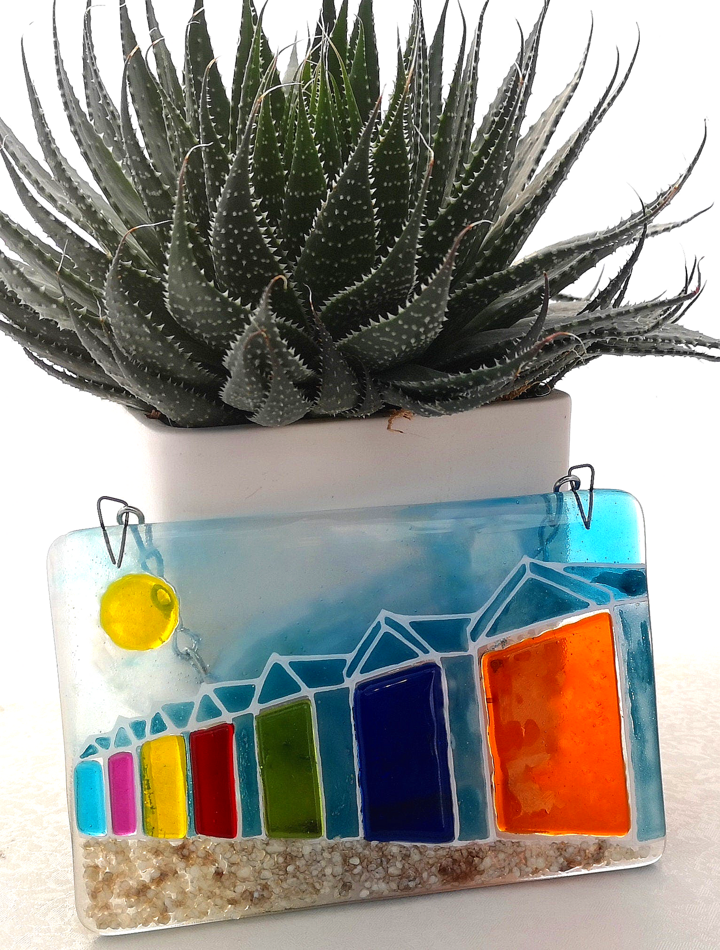 Handmade fused glass 3D Beach Huts Hanging Picture. Seaside suncatcher wall art, beach gift decoration, sea ocean scene with glass pebbles, rainbow coloured beach huts, sun and blue sky.