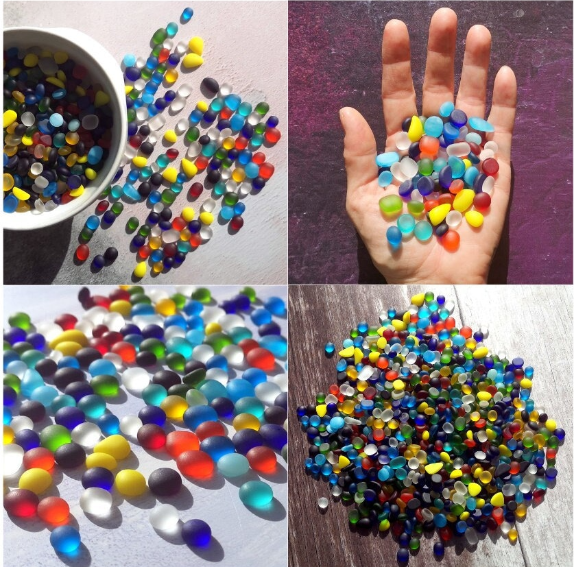 Small tumbled glass pieces in a mix of vibrant colors, spread out to showcase their varied sizes and frosted sea glass texture, ideal for crafting