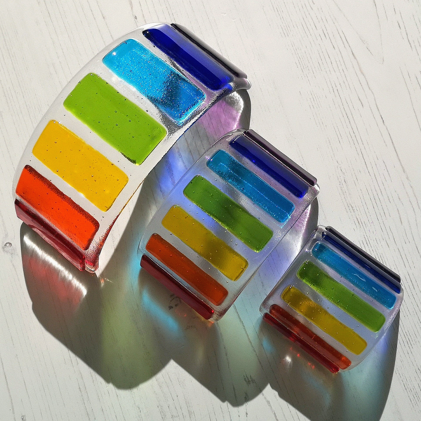 Handmade fused glass curved rainbow bridge. 3D pet paw prints. Free standing personalised 3D name rainbow arch. Brightly coloured glass gift. Suncatcher, light catcher. Gift for pet loss, remembrance.