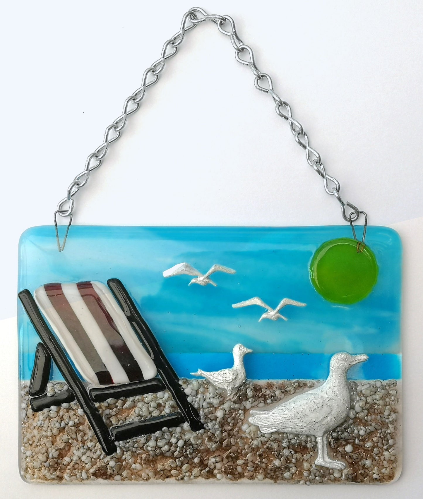 Handmade fused glass 3D Seagull & Deckchair Hanging Picture. Seaside suncatcher wall art, beach gift decoration, sea ocean scene with glass pebbles, sea birds, sun and blue sky.