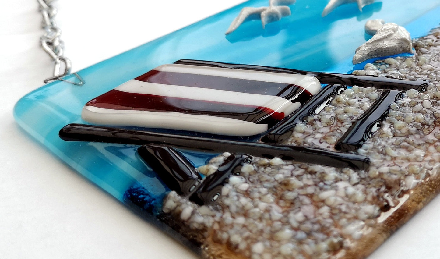 Handmade fused glass 3D Seagull & Deckchair Hanging Picture. Seaside suncatcher wall art, beach gift decoration, sea ocean scene with glass pebbles, sea birds, sun and blue sky.