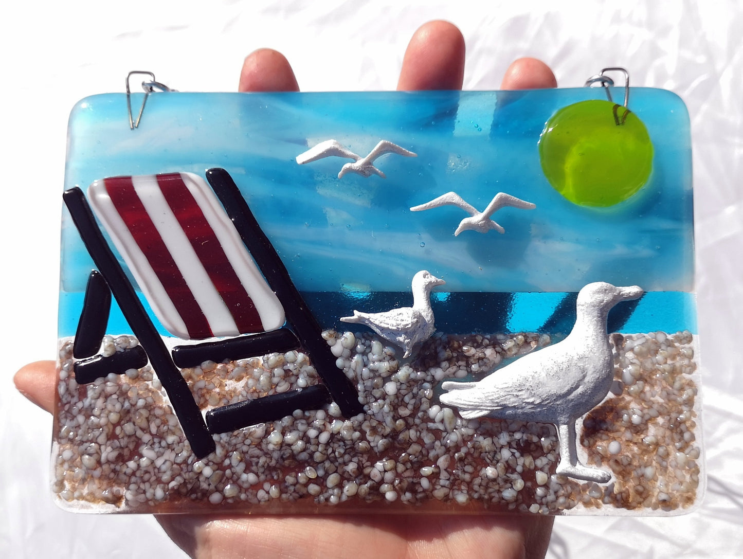 Handmade fused glass 3D Seagull & Deckchair Hanging Picture. Seaside suncatcher wall art, beach gift decoration, sea ocean scene with glass pebbles, sea birds, sun and blue sky.