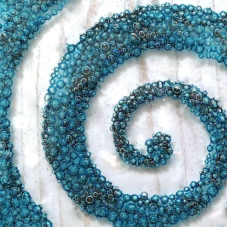 Handmade fused glass spiral drinks coaster with embedded coloured bubbles. Glass wall tile, hot drink table mat, twirl design, swirly pattern gift. Bubbly home decoration, dining table protection.