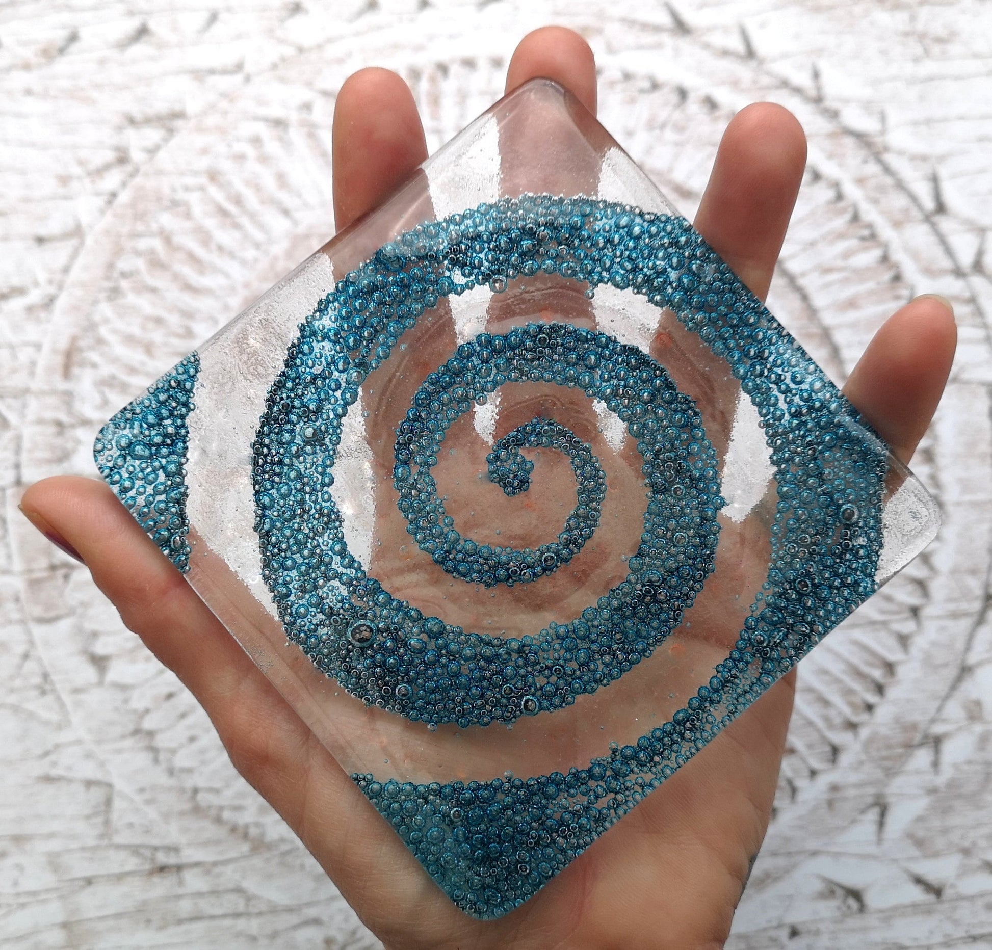 Handmade fused glass spiral drinks coaster with embedded coloured bubbles. Glass wall tile, hot drink table mat, twirl design, swirly pattern gift. Bubbly home decoration, dining table protection.