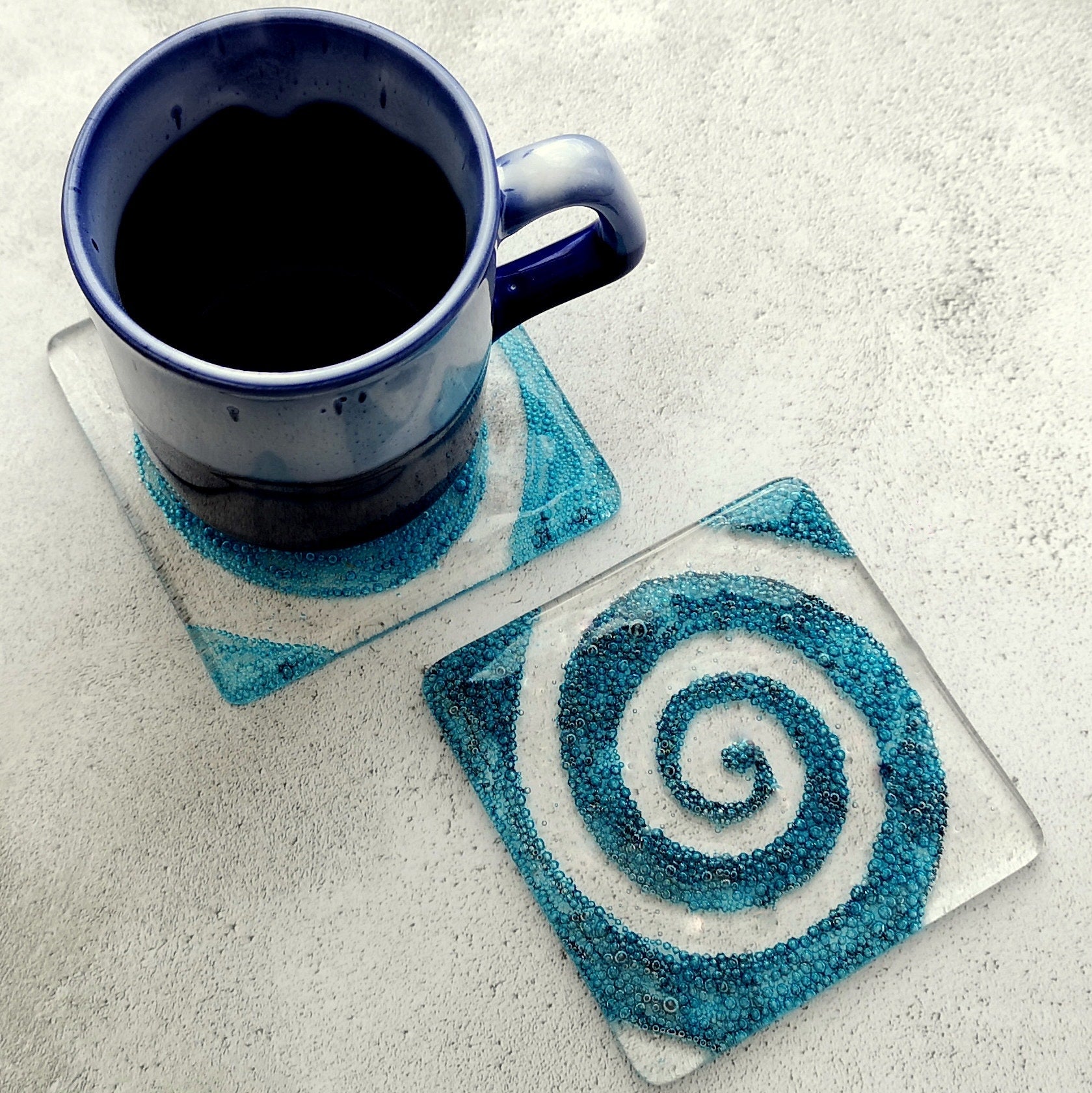 Handmade fused glass spiral drinks coaster with embedded coloured bubbles. Glass wall tile, hot drink table mat, twirl design, swirly pattern gift. Bubbly home decoration, dining table protection.