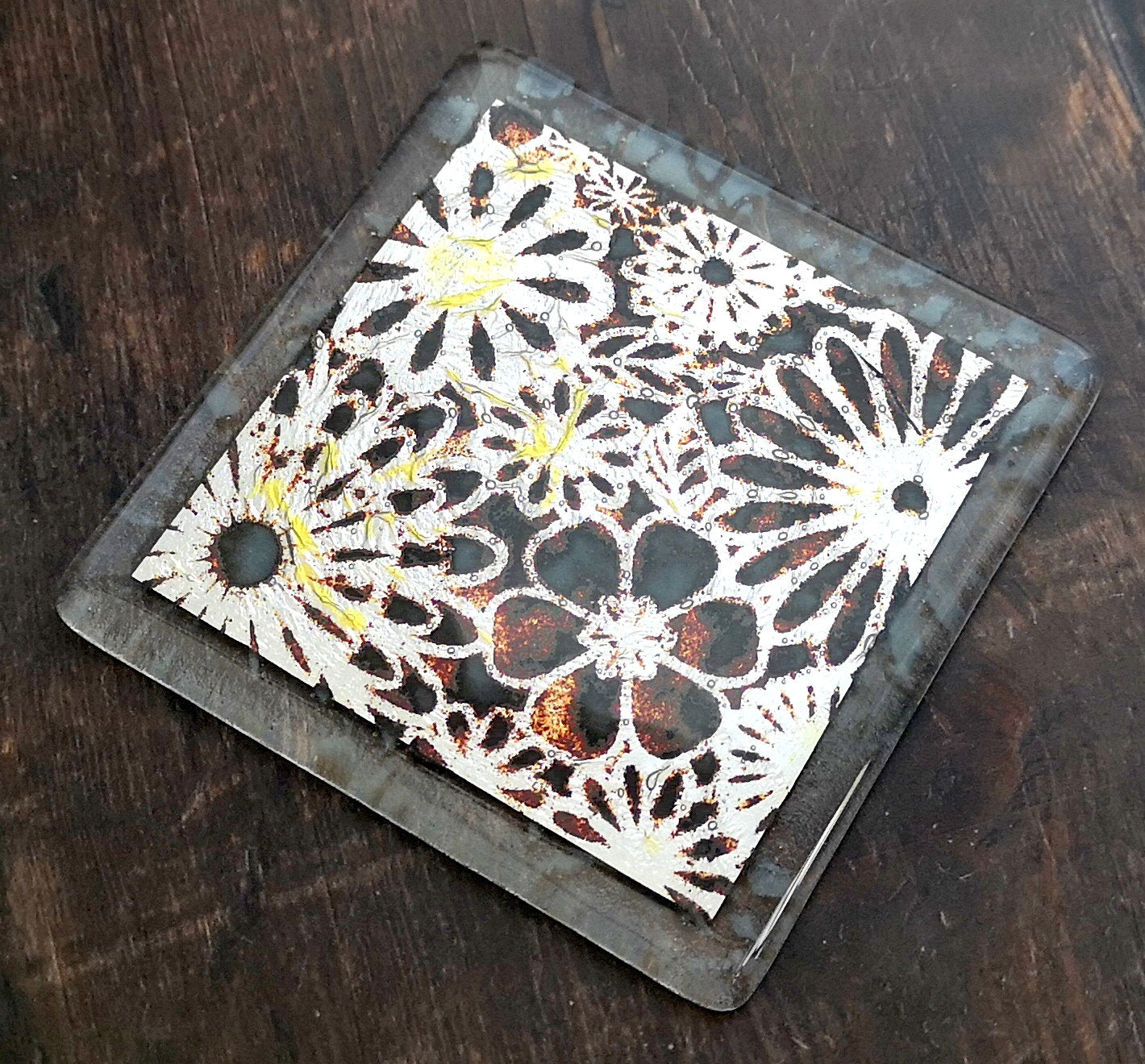 Handmade fused glass flowers on silver drinks coaster. Flower pattern design, glass tile art, hot drink table mat, floral nature gift. Embedded pure silver foil, wall tile home decoration, dining table protection.