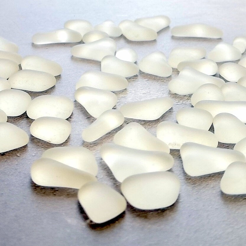 Close-up of various-sized clear tumbled glass pieces, highlighting their unique frosted textures and resemblance to naturally weathered sea glass