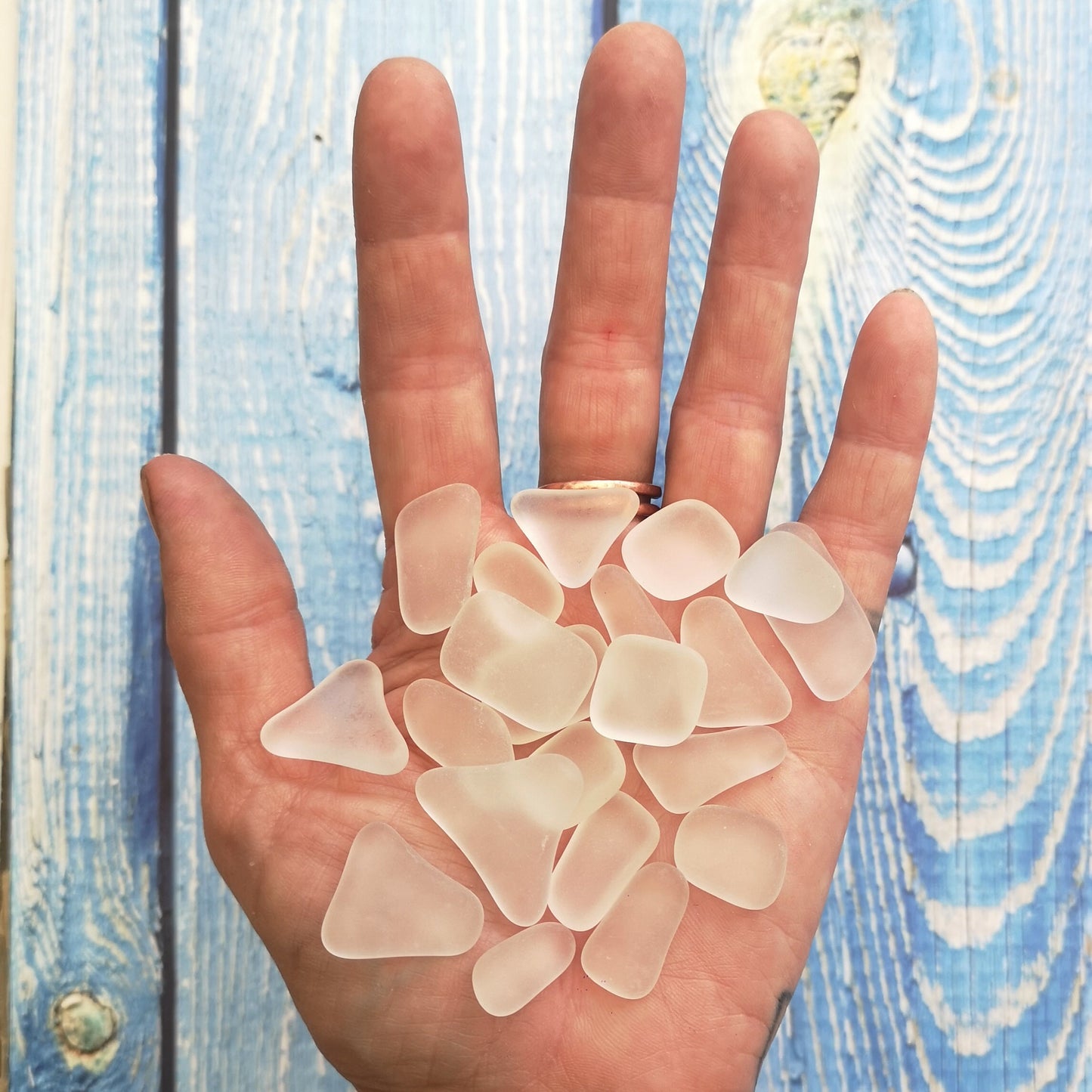 A handful of white frosted tumbled glass pieces in clear tones, capturing their subtle beauty and suitability for unique art creations
