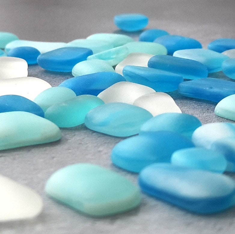 Close-up of light blue, turquoise, and clear tumbled glass, emphasizing their unique frosted textures and subtle colour differences, ideal for DIY projects