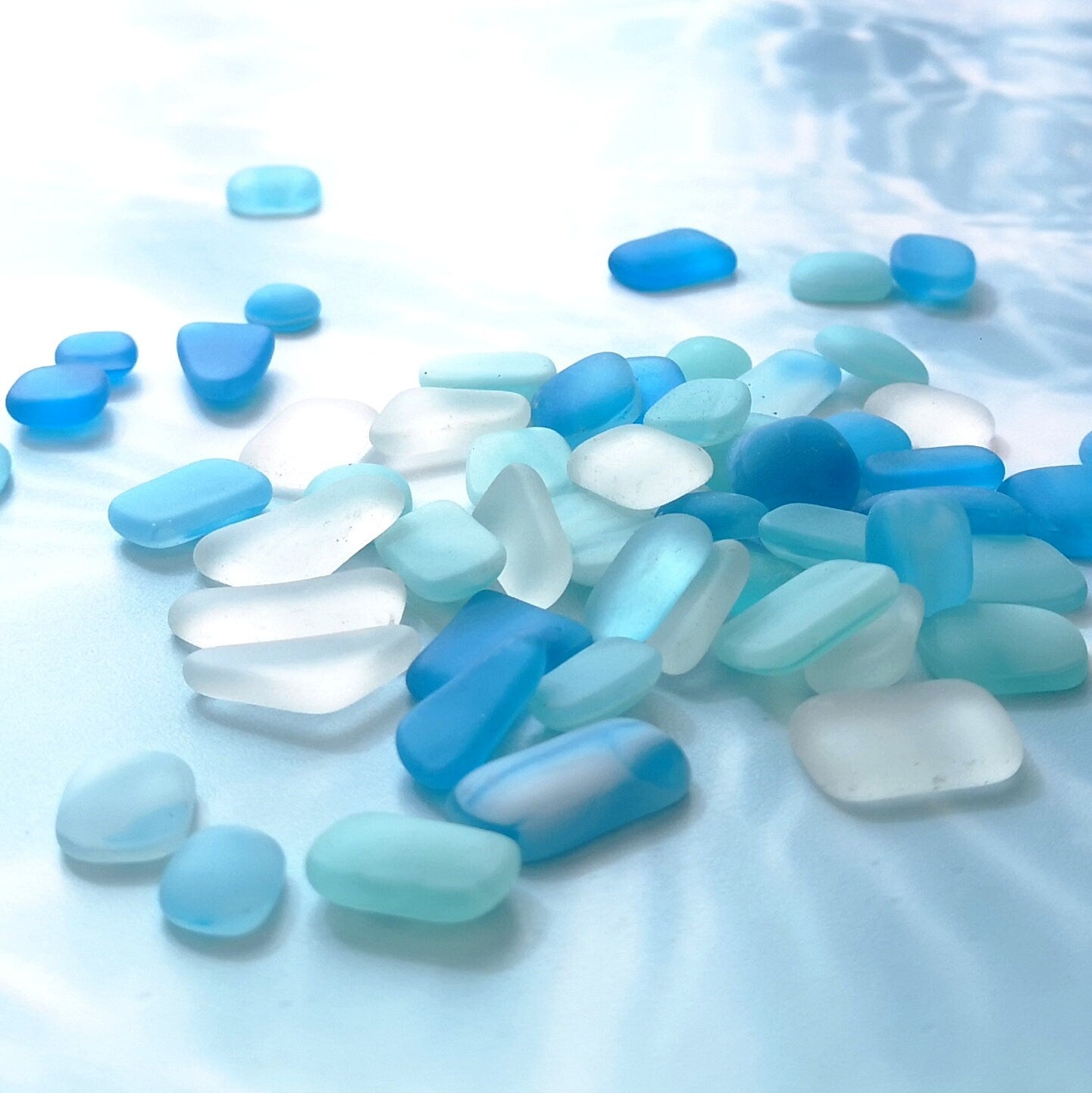 Inspiring display of light blue, turquoise, and clear tumbled glass, for use in decorative home crafts
