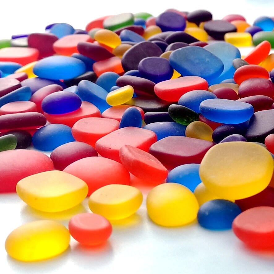 Display of rainbow-coloured tumbled glass, arranged to inspire artistic endeavours, emphasizing their size variety and colourful charm