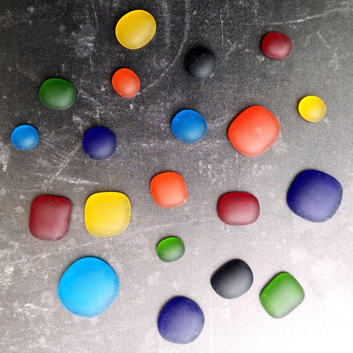 Rainbow-coloured tumbled glass assortment, neatly arranged, emphasizing their diverse sizes and potential for artistic use