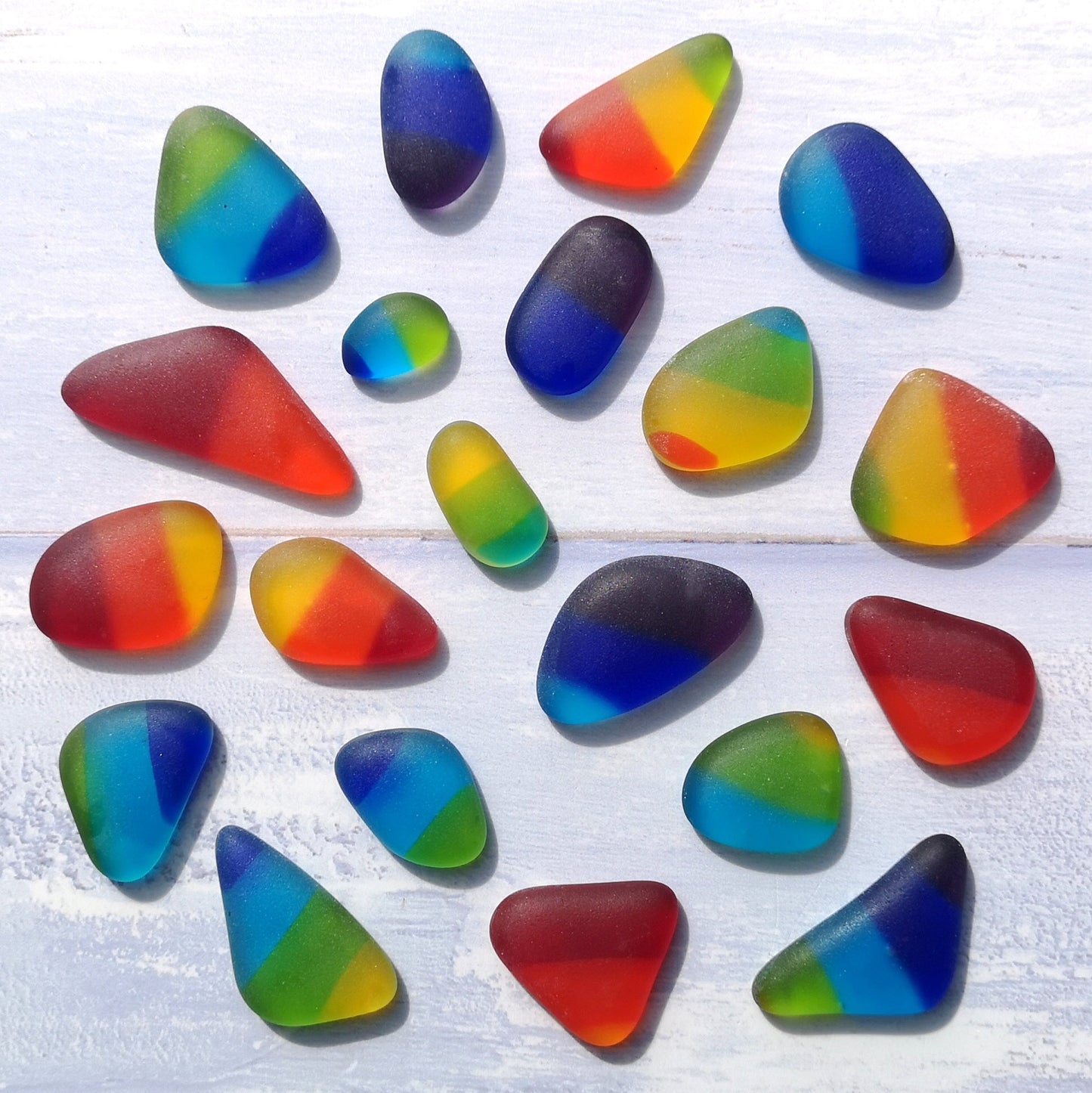 Collection of multicolored tumbled glass pieces, arranged in a visually appealing pattern, emphasizing their diverse sizes and creative potential