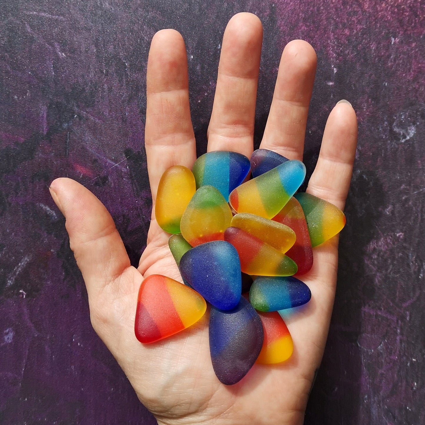 Handful of vibrant, multicolored tumbled glass pieces, capturing their distinct, weathered look, suitable for unique and personalized art creations