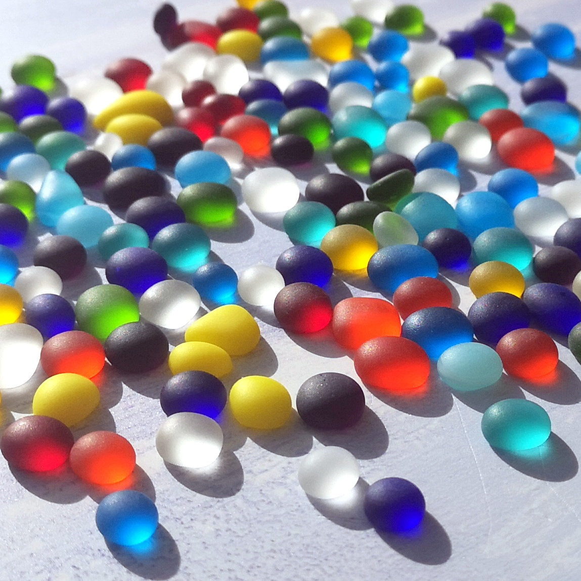 Close-up of tiny, colourful tumbled glass bits, highlighting their various shades and frosted finish, perfect for detailed mosaic projects