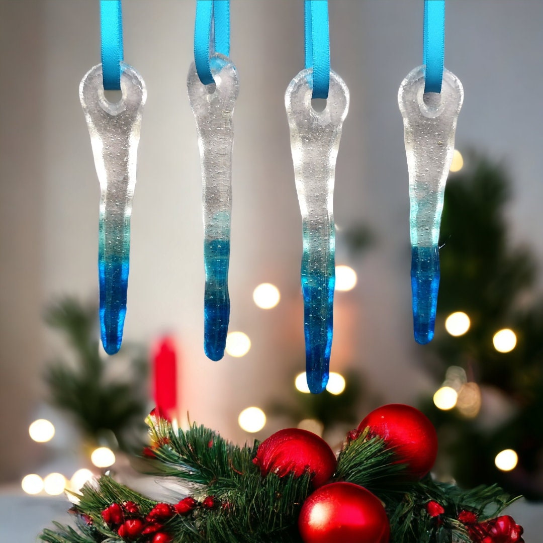 Set of four glass icicle decorations, with colours changing from clear to blue tips, displayed against a festive bauble backdrop, capturing their sparkling, frost-like appearance in natural light