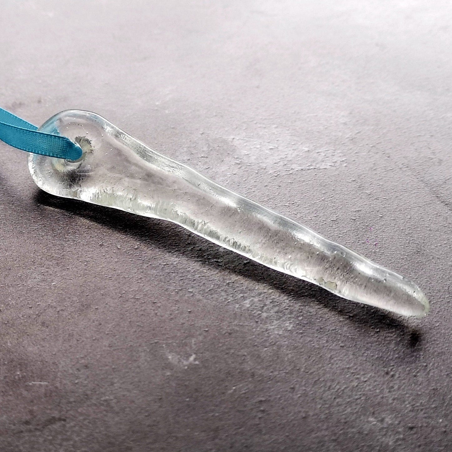 Close-up of a single clear glass icicle ornament, emphasizing its handcrafted detail and icy glass finish.