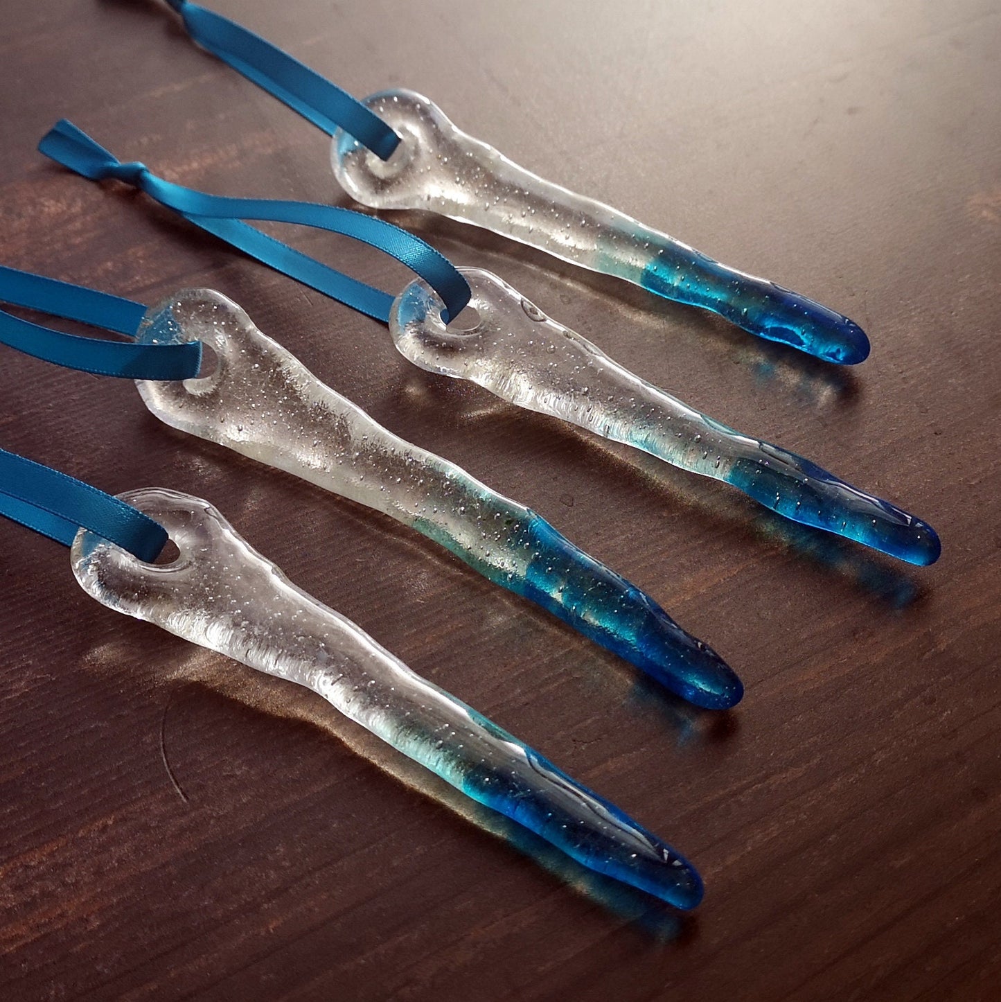 Handcrafted blue-tipped icicle decorations, against a dark background, emphasizing their striking colour contrast and detail