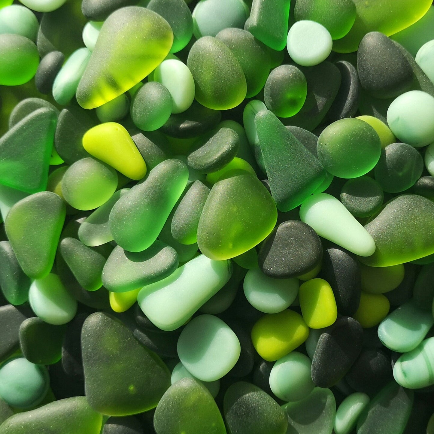 Eco-friendly green tumbled glass assortment, highlighting their sustainable appeal and varied hues