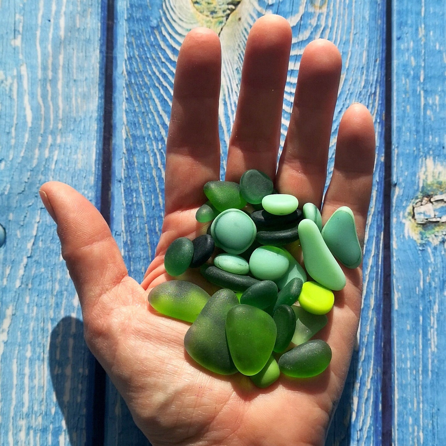 A handful of green-coloured tumbled glass pieces, with an emphasis on their unique, weathered appearance, ideal for custom artwork