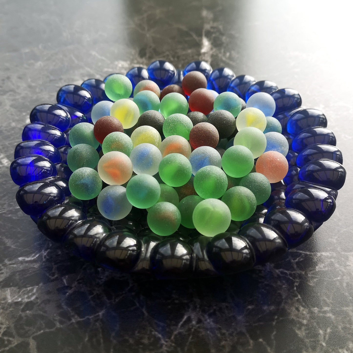 Artistic display of multicoloured tumbled glass marbles, set out to inspire creative DIY projects, emphasizing their size variety and visual appeal