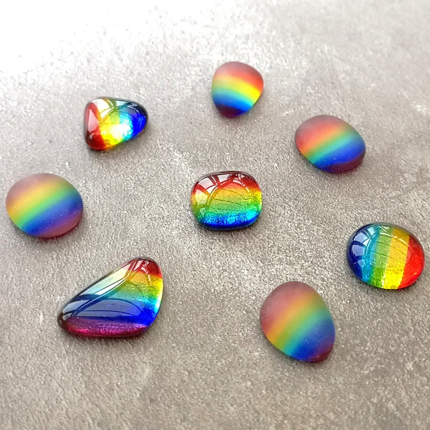 Close-up view of assorted Little Rainbows in a polished or tumbled glass finish, highlighting their unique shiny or frosted textures and shapes, perfect for DIY projects