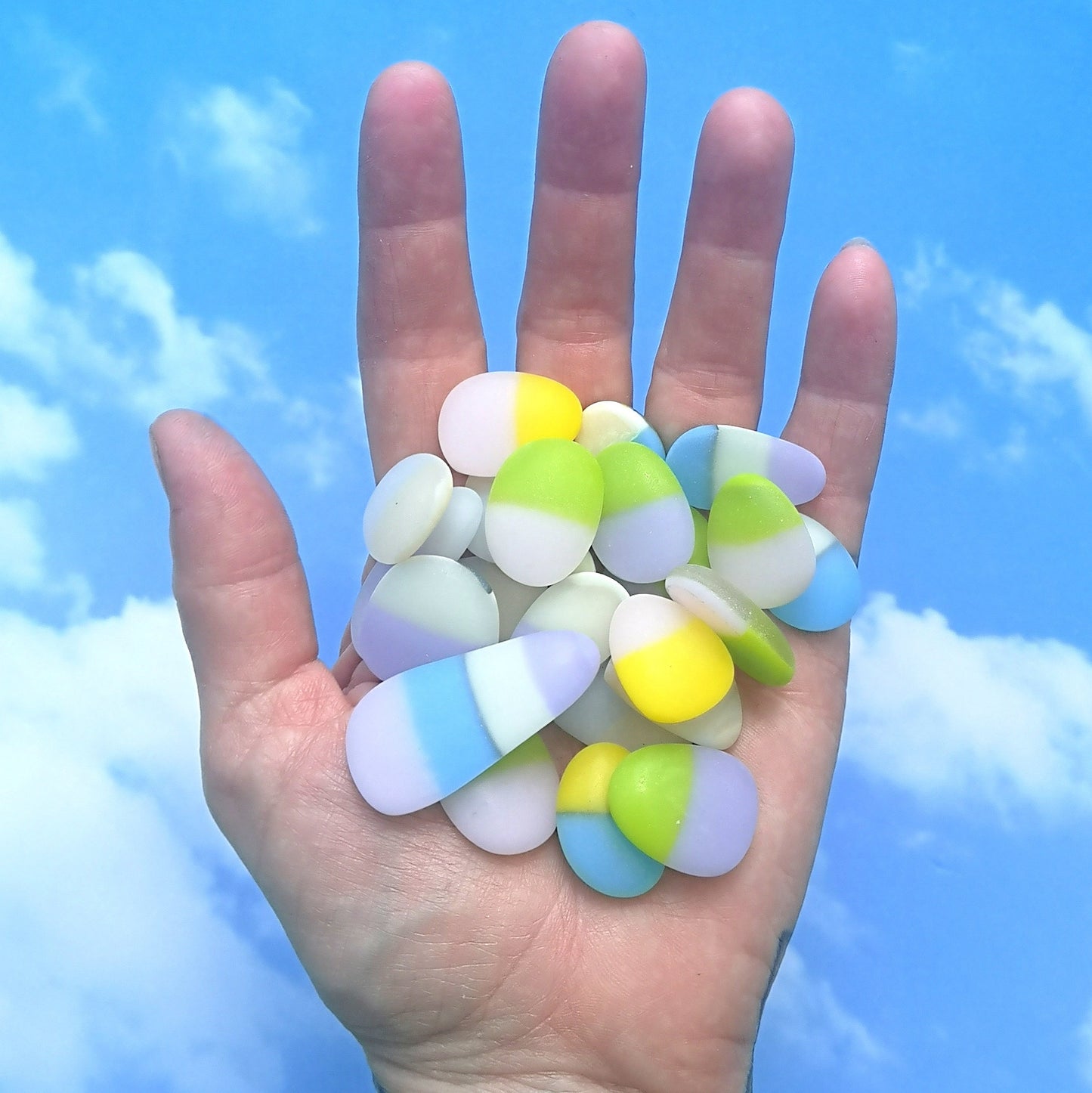 Handful of opaque pastel, multicoloured tumbled glass pieces, capturing their distinct, weathered look, suitable for unique and personalized art creations