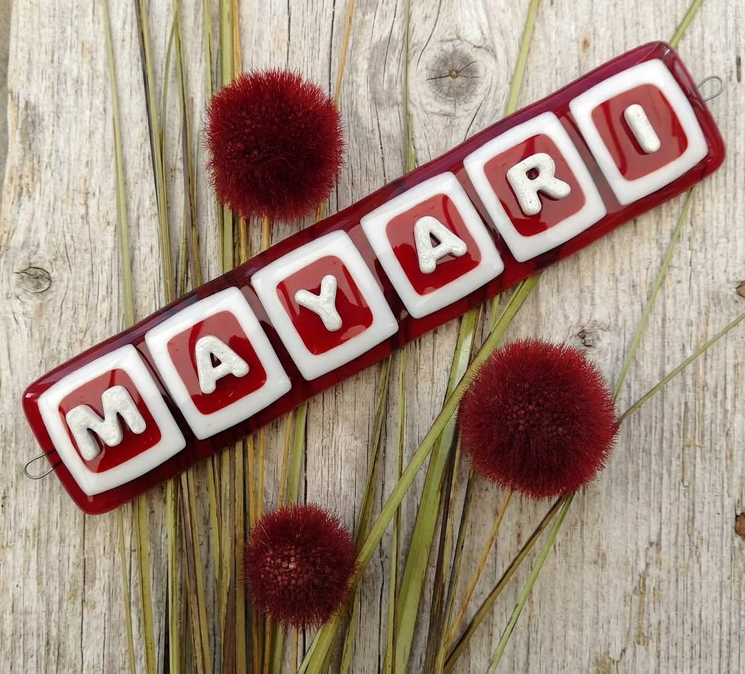 Handmade fused glass personalised name sign. Customised 3D name plaque. Child's name door sign. Colourful name plate, new baby gift. Expecting Mum present. Displayed on a rustic wood background with dried flowers.